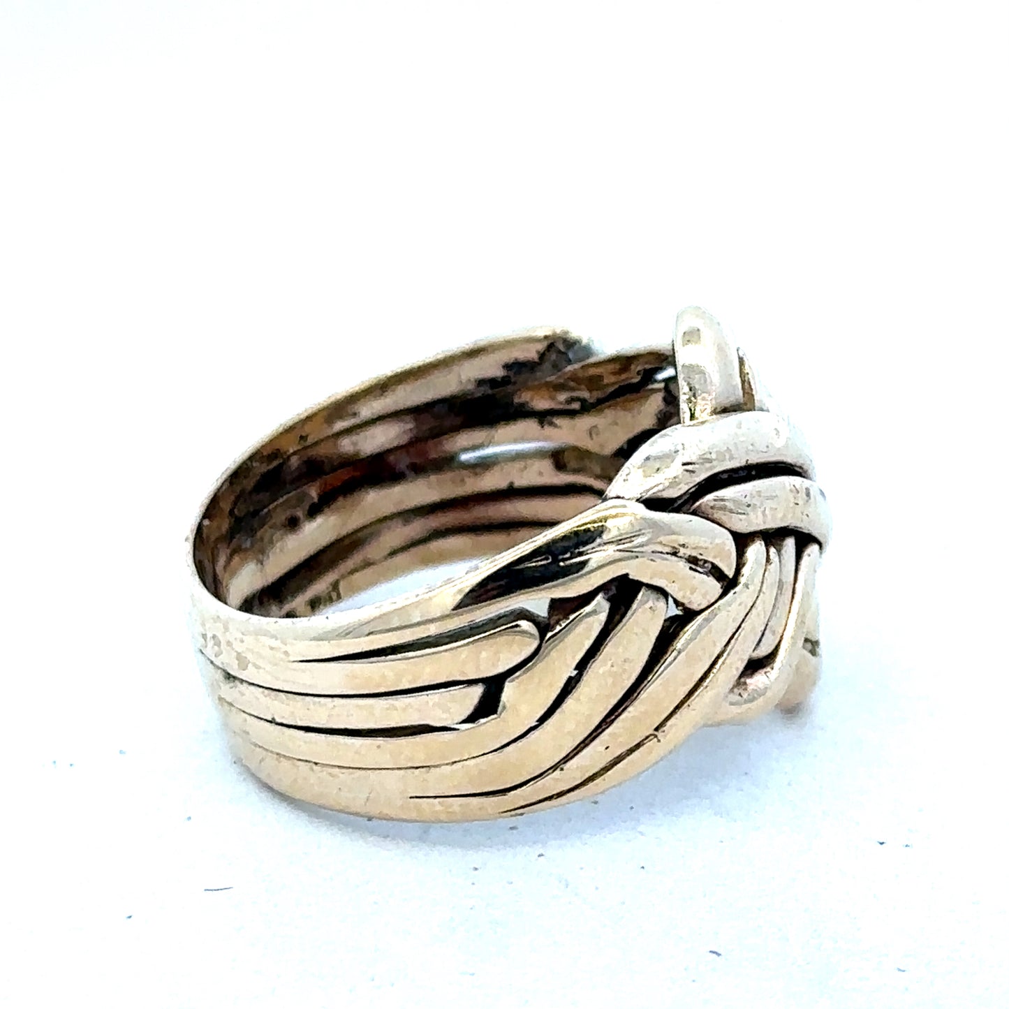 9ct yellow gold puzzle ring in size U with interlocking band design by Reeves and Sons, shown from a side angle.