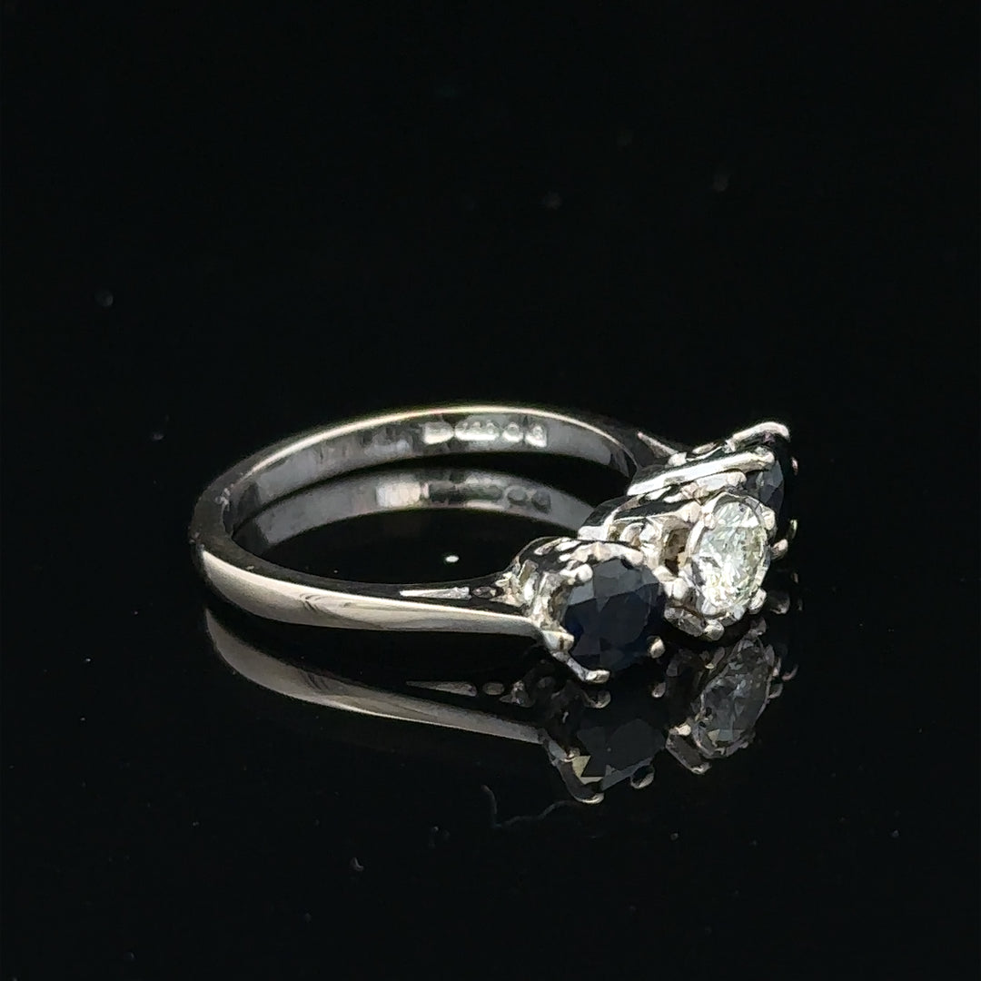 18ct white gold sapphire and diamond ring with a central blue sapphire and sparkling diamonds, displayed on a neutral background.