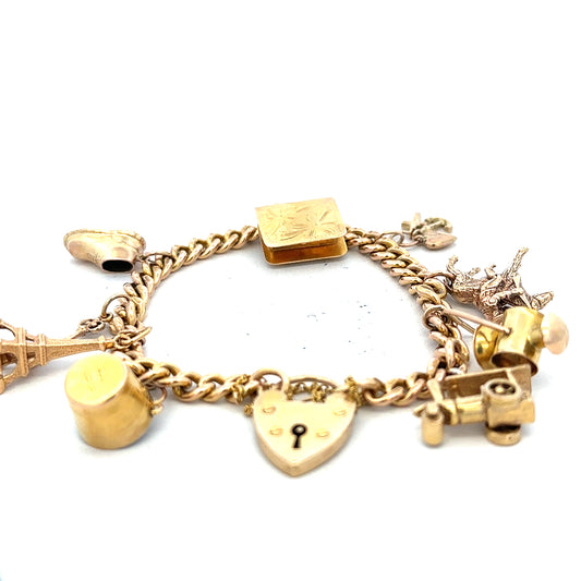 9ct yellow gold charm bracelet with detailed charms, weighing 28.1g, featuring intricate gold craftsmanship.