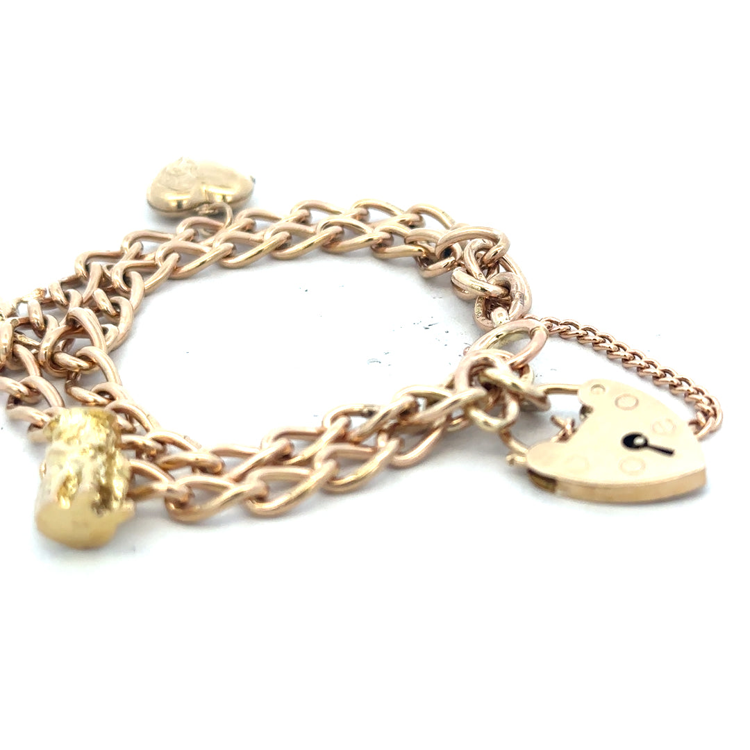 9ct yellow gold charm bracelet weighing 28.5g with intricate charms and links, unbranded, displayed on a neutral background.