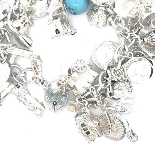 Silver charm bracelet weighing 128.8g with various charms, unbranded jewelry accessory, shown in a close-up image.