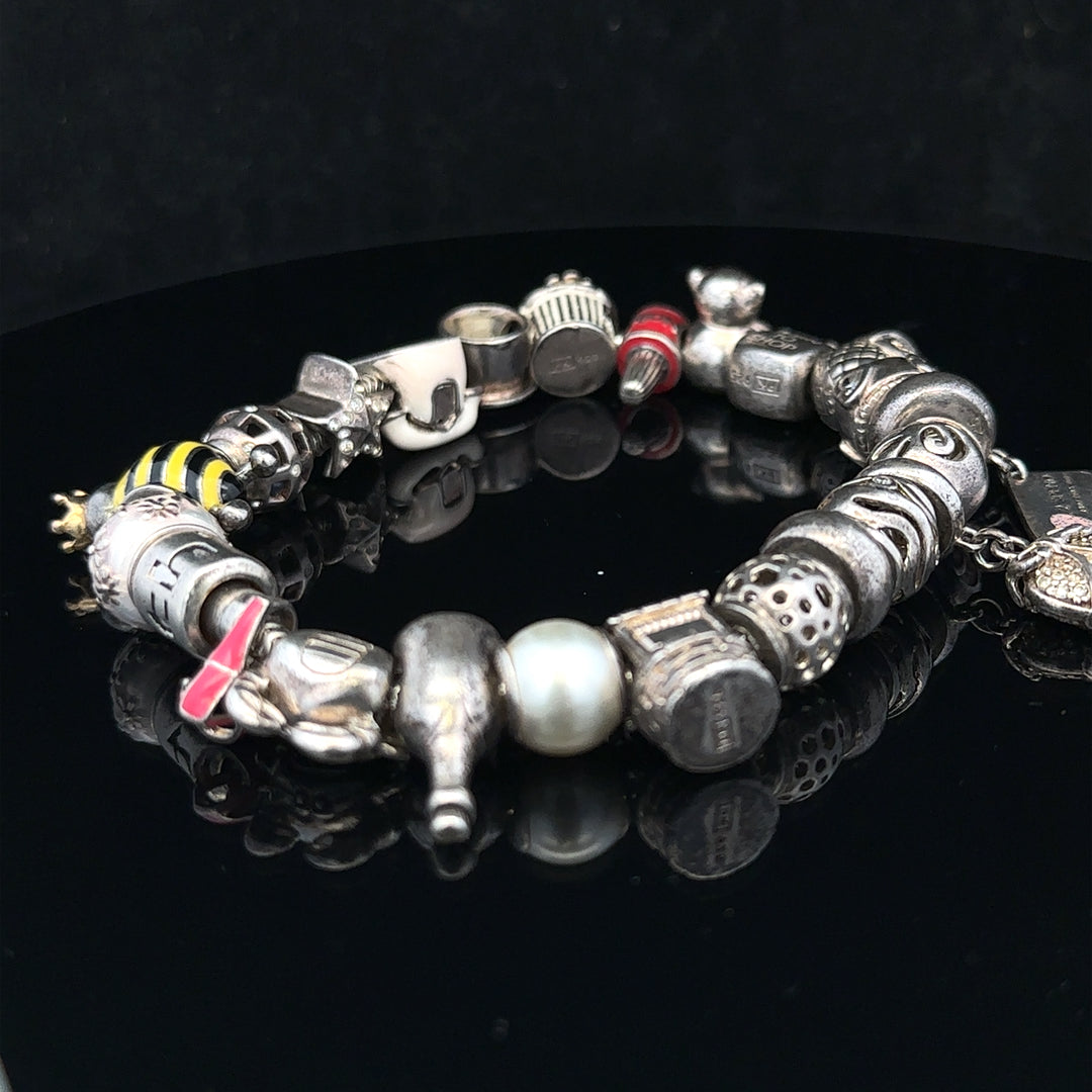 Silver charm bracelet with multiple charms, unbranded, featuring a 64.8 cm length and intricate design.