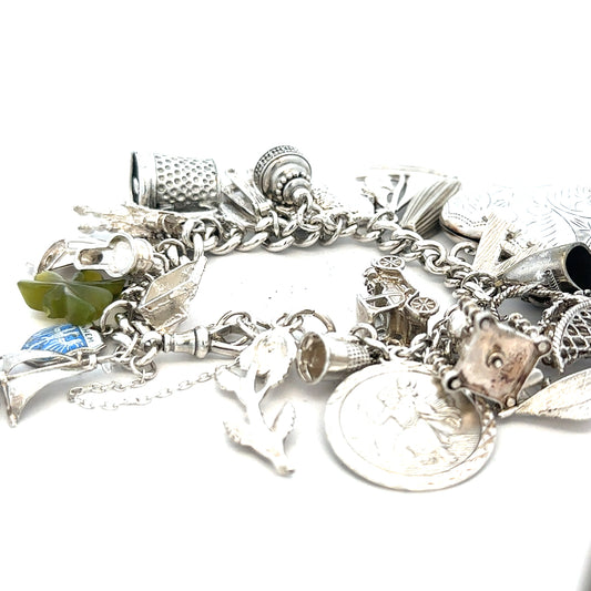 Silver charm bracelet weighing 83.4g with various decorative charms, unbranded jewelry accessory on a neutral background.