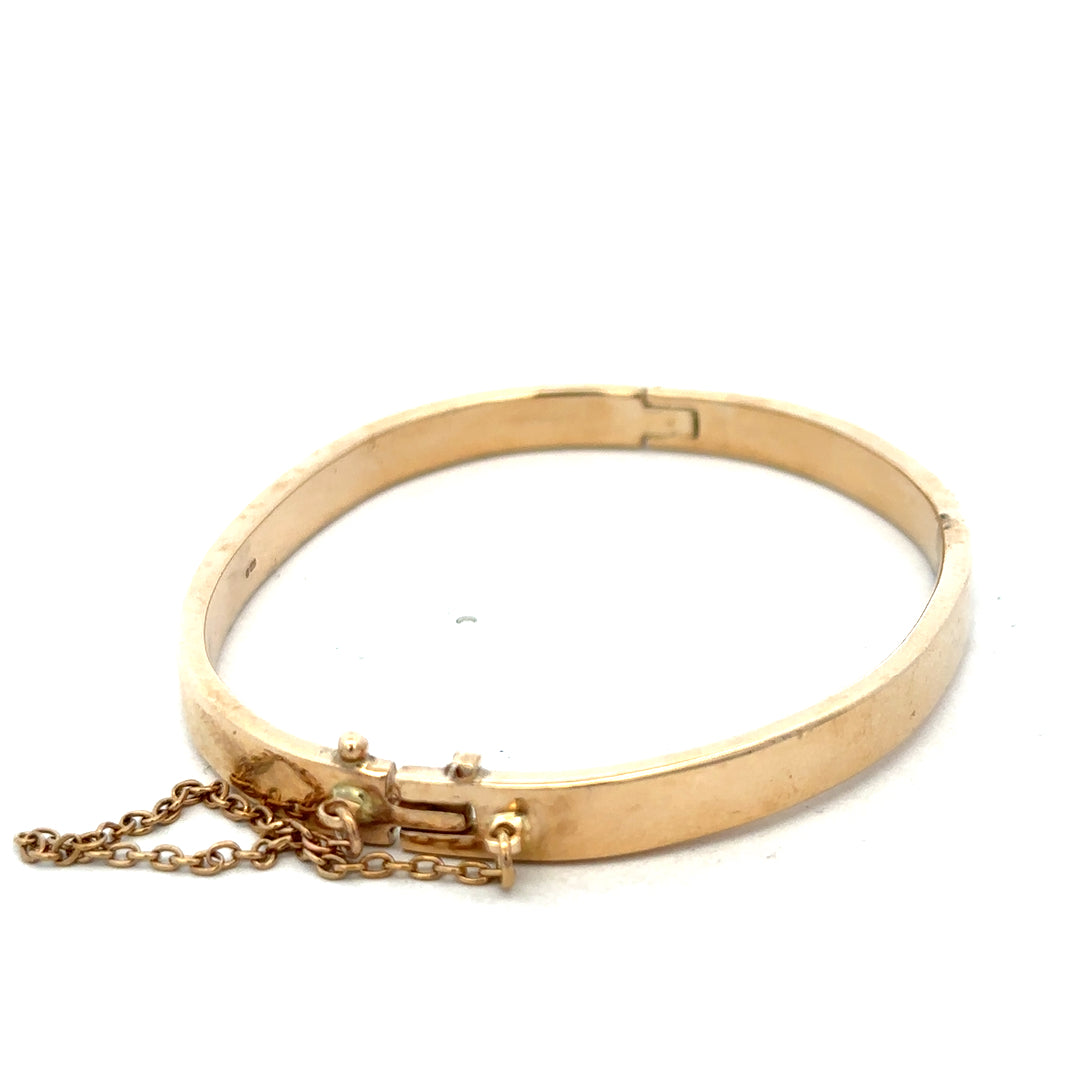 9ct yellow gold bangle bracelet by Reeves and Sons, weighing 24.1g, with a smooth polished finish and classic design.