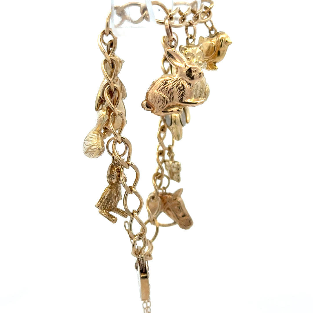 9ct yellow gold charm bracelet by Reeves and Sons, featuring intricate charms and a secure clasp, weighing 13.4g.