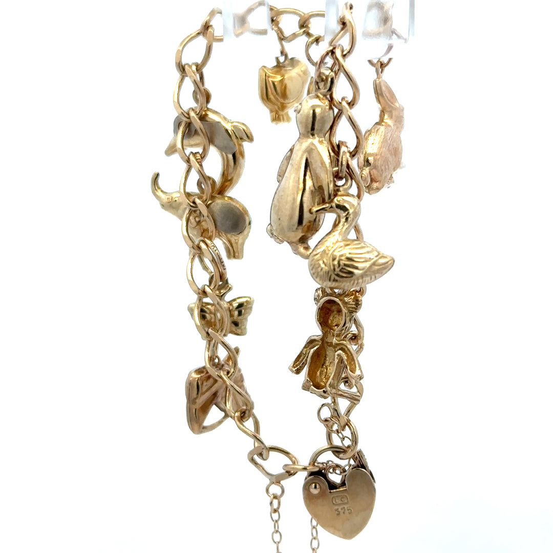 9ct yellow gold charm bracelet by Reeves and Sons, 13.4g, featuring intricate charms and a secure clasp.