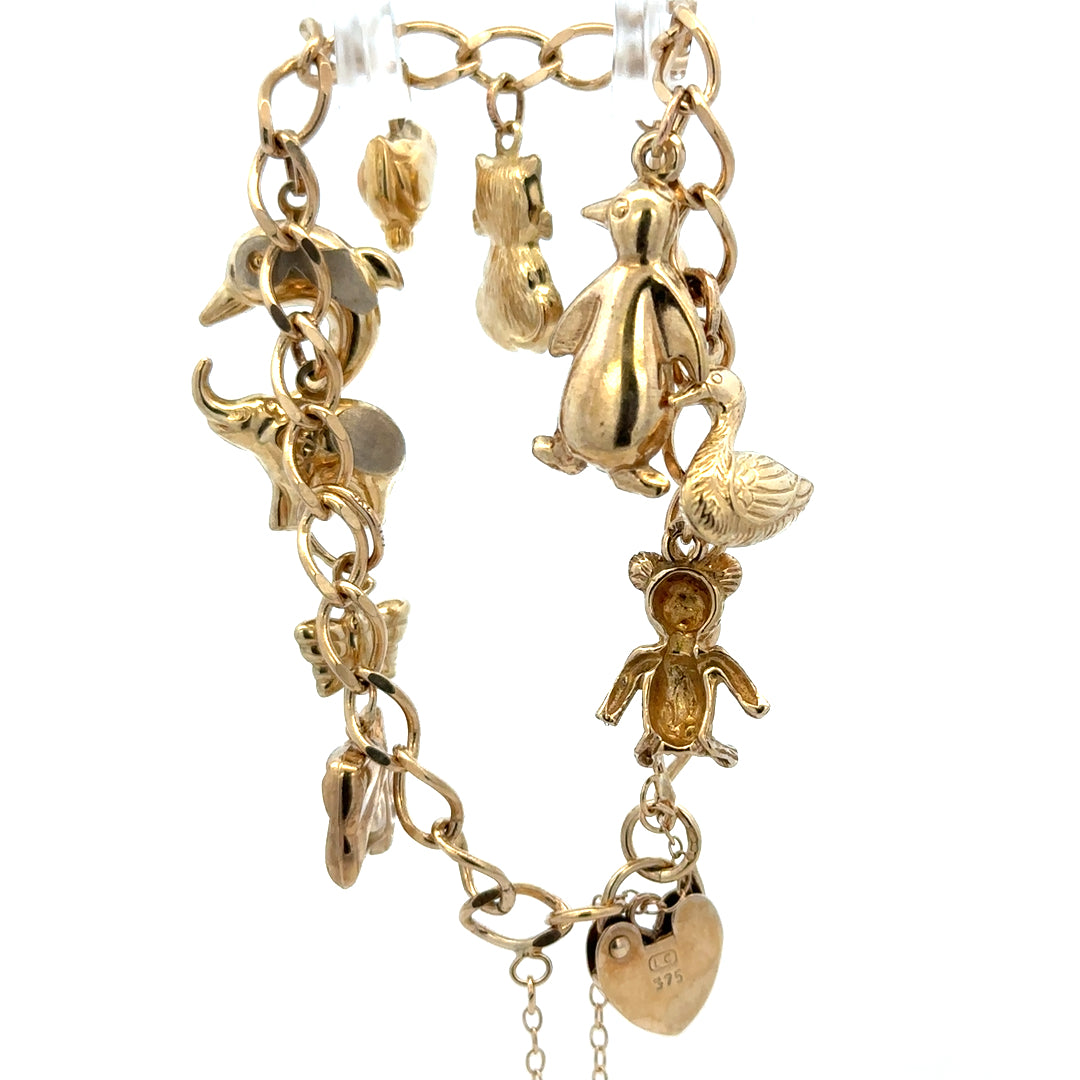 9ct yellow gold charm bracelet by Reeves and Sons with delicate chain and small decorative charms, weighs 13.4g.