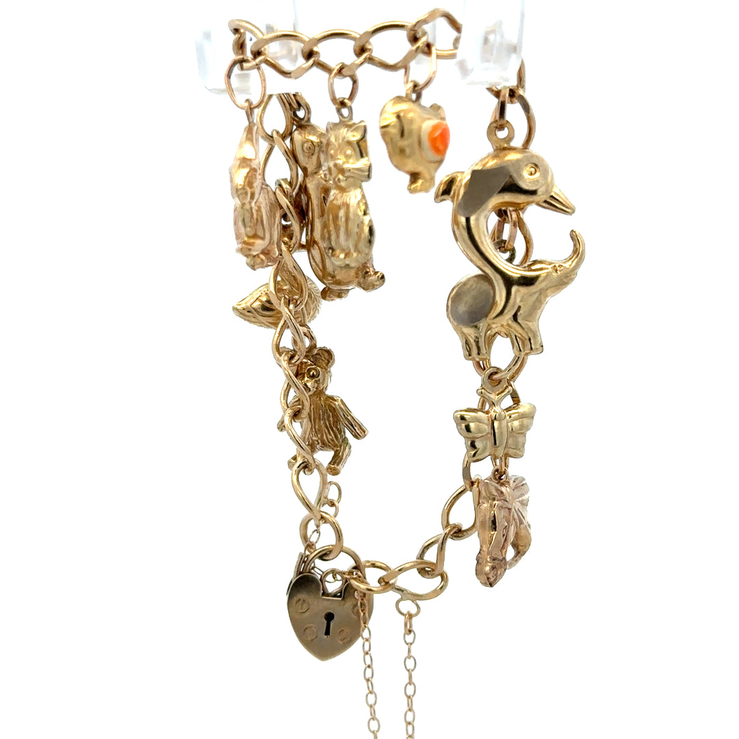 9ct yellow gold charm bracelet by Reeves and Sons with intricate details and multiple charms, weighing 13.4g.