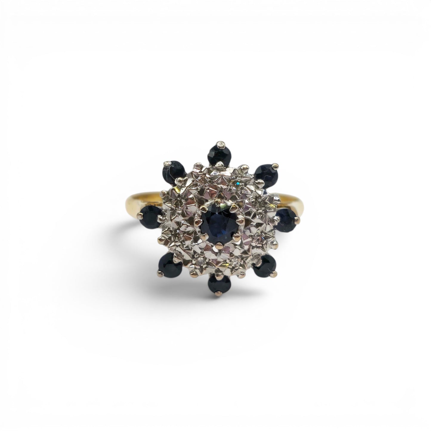 18ct yellow gold sapphire and diamond cluster ring by Reeves and Sons, showcasing a vibrant central sapphire surrounded by sparkling diamonds.