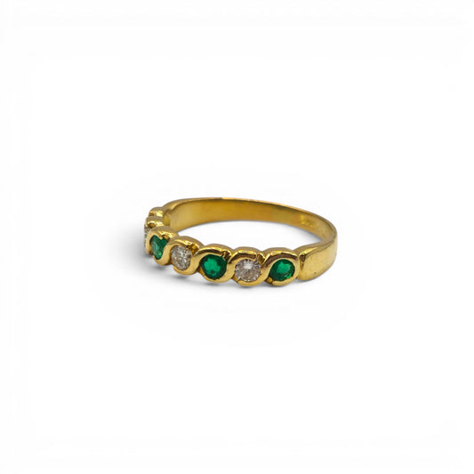 18ct yellow gold half eternity ring with emeralds and diamonds by Reeves and Sons, showcasing sparkling gemstones and elegant design.