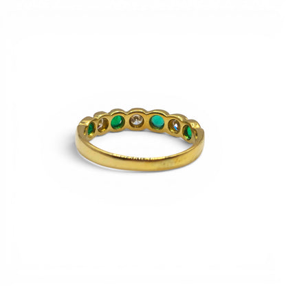 18ct yellow gold half eternity ring with emeralds and diamonds, featuring a sleek band and sparkling gemstone accents.