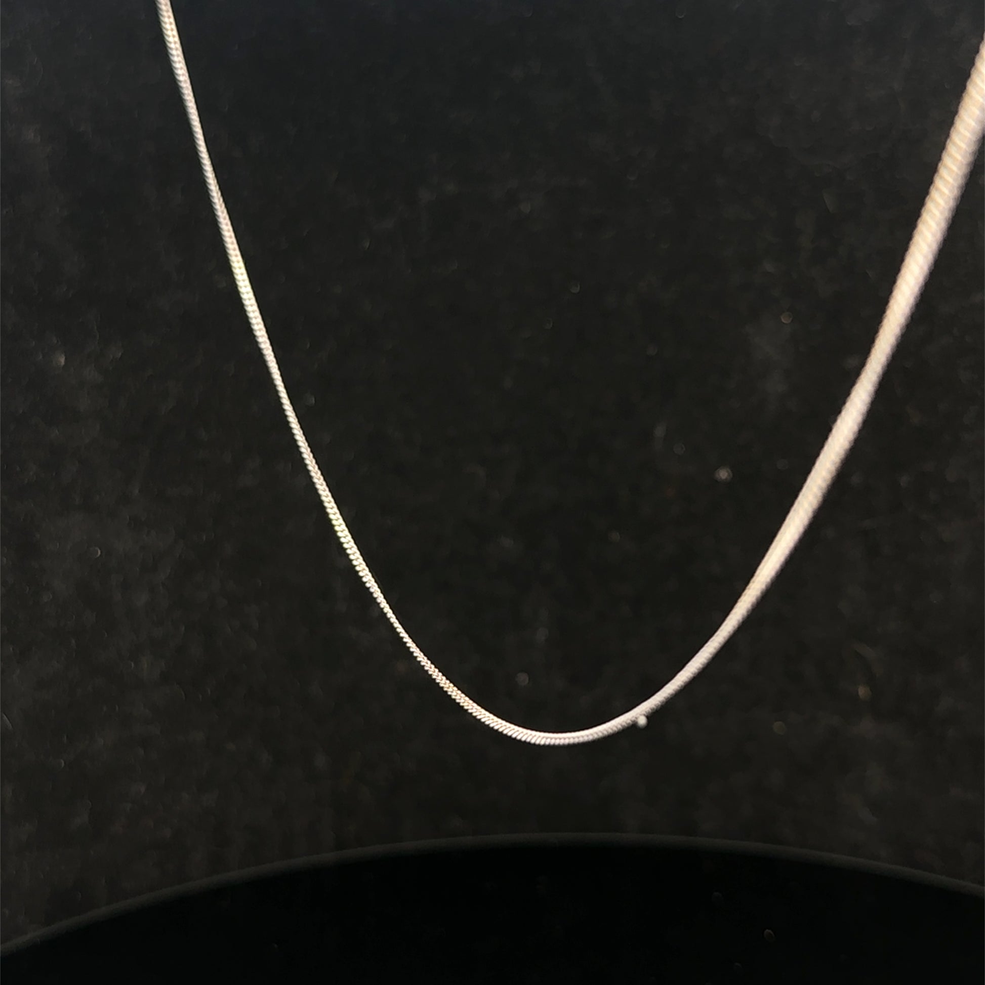 9ct white gold chain weighing 1.5g, featuring a delicate link design from Reeves and Sons, shown in a close-up image.
