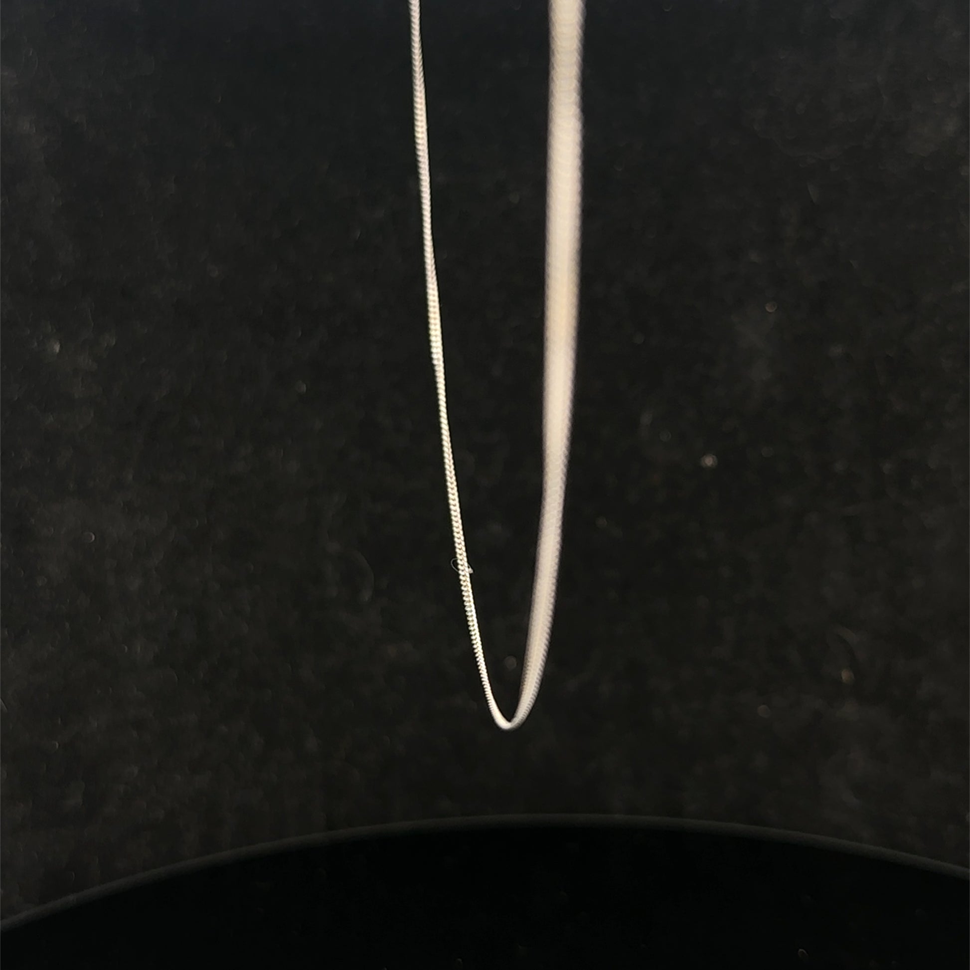 9ct white gold chain weighing 1.5g with a delicate link design from Reeves and Sons, shown in close-up.