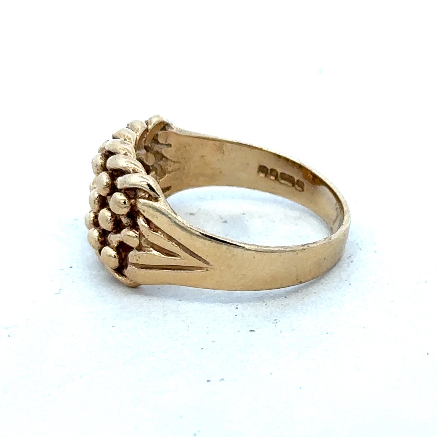 9ct yellow gold keeper ring size T1/2 with a smooth band, crafted by Reeves and Sons, shown in a close-up image.