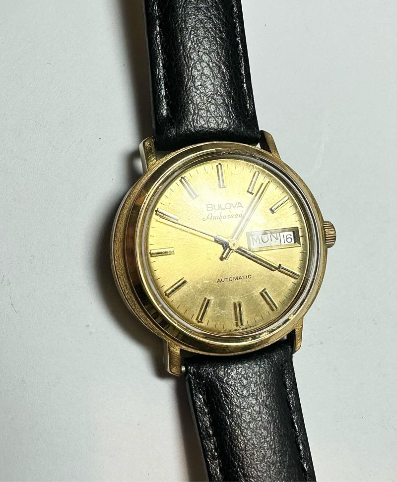 Bulova plated automatic watch with stainless steel case, weighing 44.9g, featuring a sleek design and analog display.