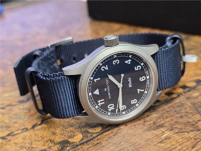 Hamilton Khaki watch Age 2025 with black dial, stainless steel case, and leather strap, displayed on a white background.