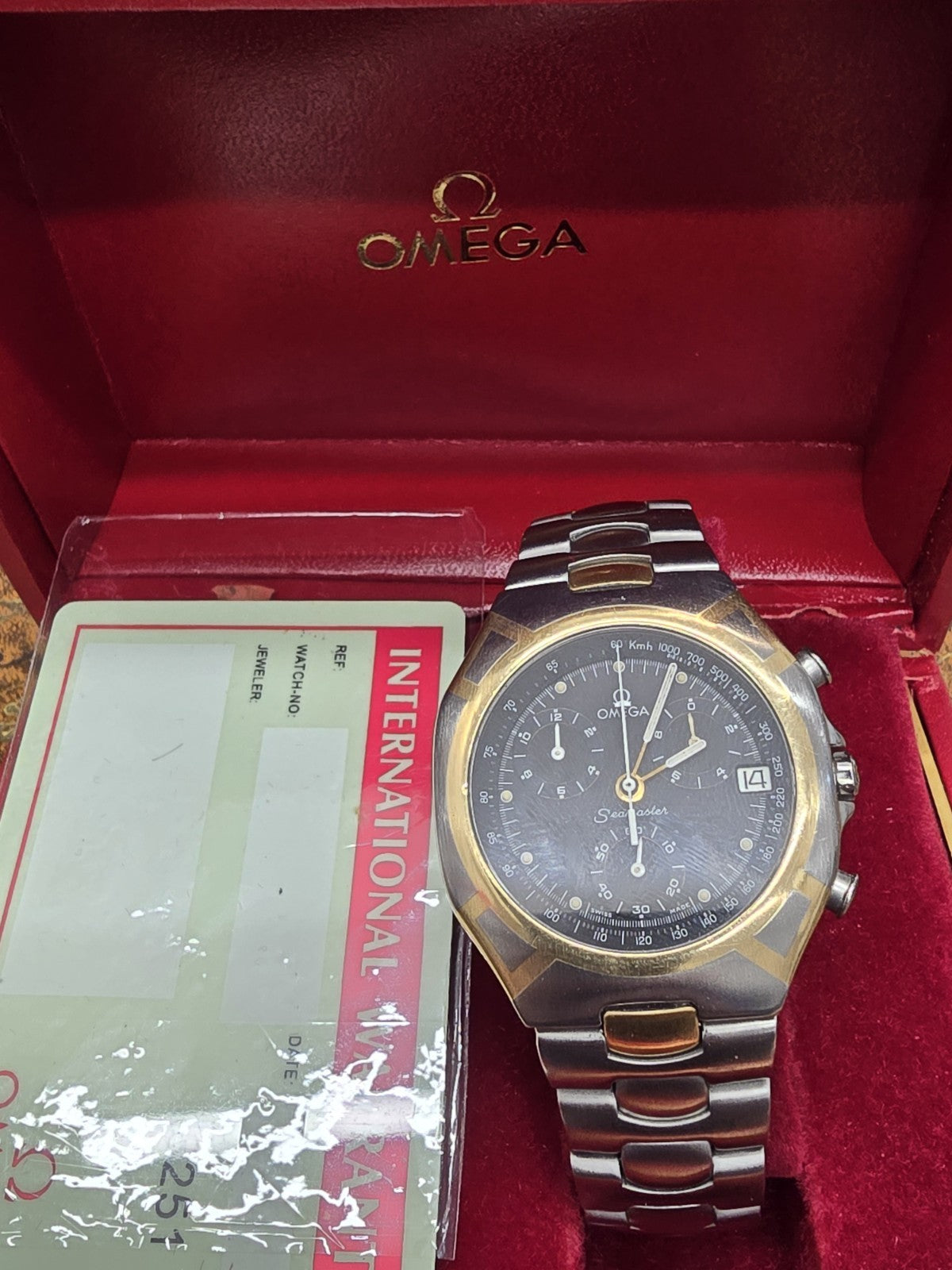 Omega Seamaster Polaris Chronograph watch with box and card, featuring a stainless steel bracelet and detailed dial display.