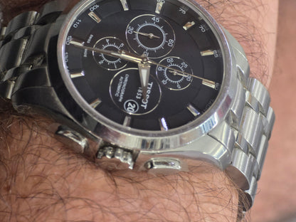 Tissot 1853 automatic chronograph watch with black dial and stainless steel bracelet, showcasing a sleek, classic design.
