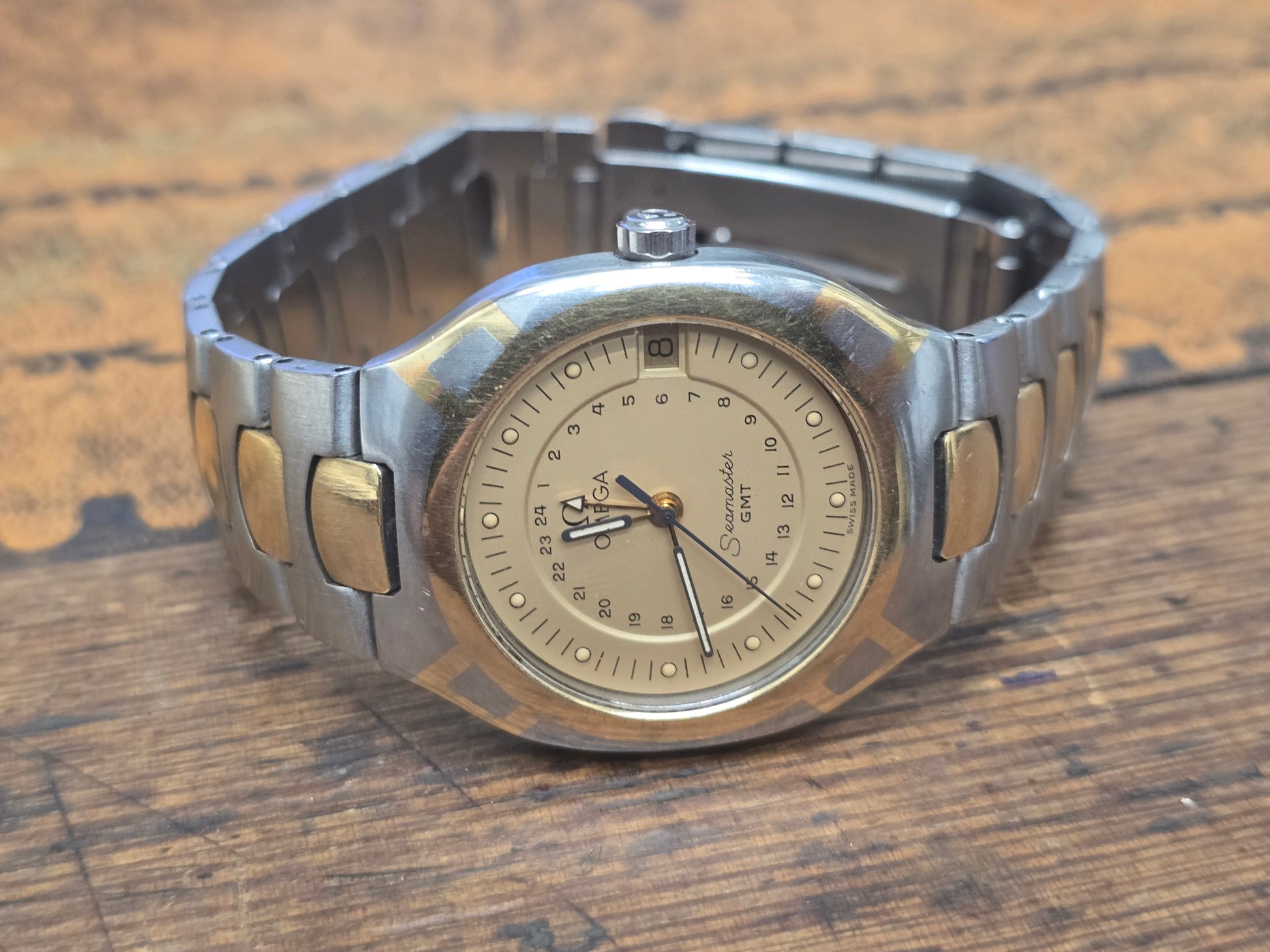 Vintage Omega Seamaster Polaris Chronograph watch with steel and gold bracelet, displaying a black dial and chronograph features.