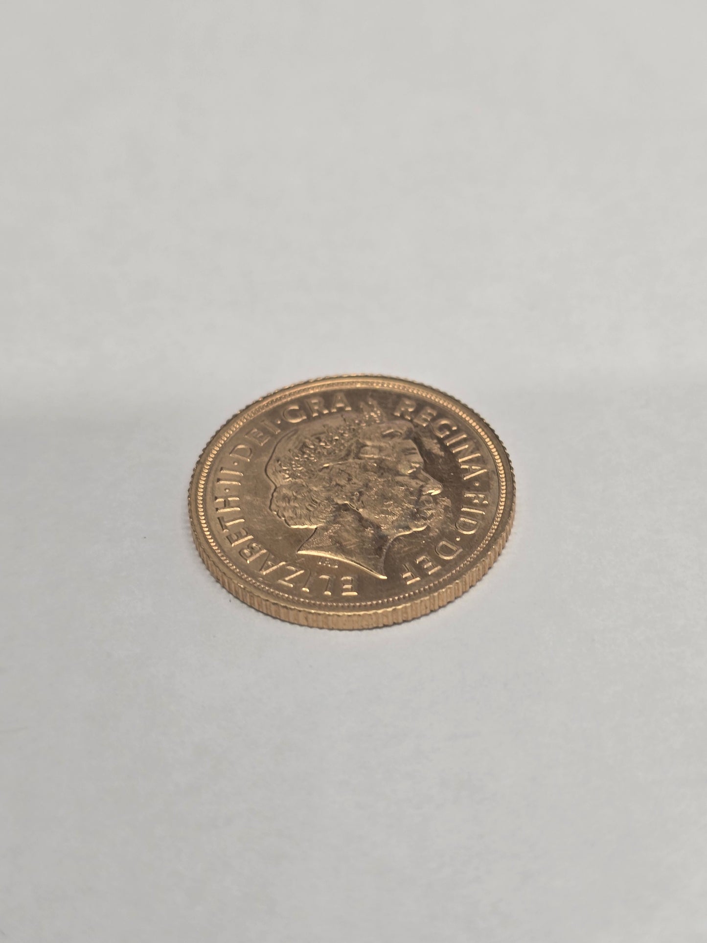 2012 Reeves and Sons full sovereign coin showing detailed portrait and inscriptions on gold-colored metal surface.
