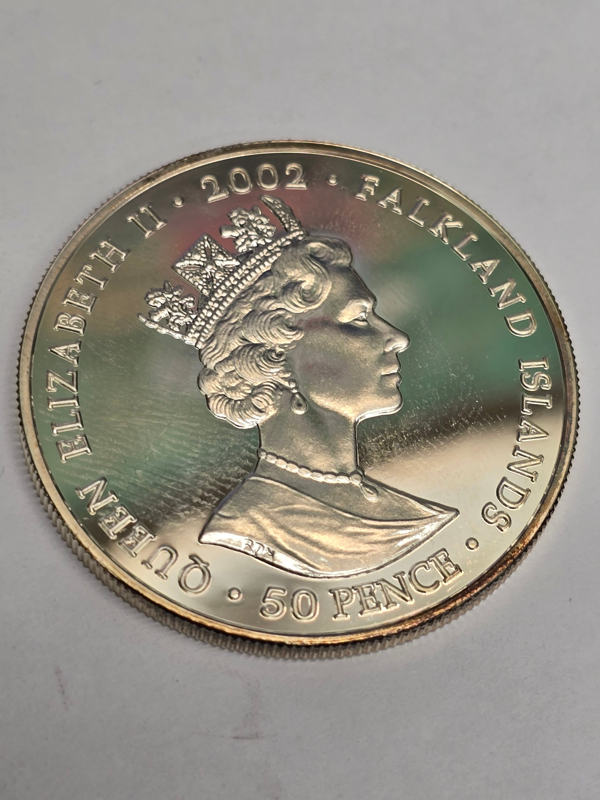 Silver 50 pence coin celebrating the 2002 Golden Jubilee, featuring detailed designs, minted by Reeves and Sons.