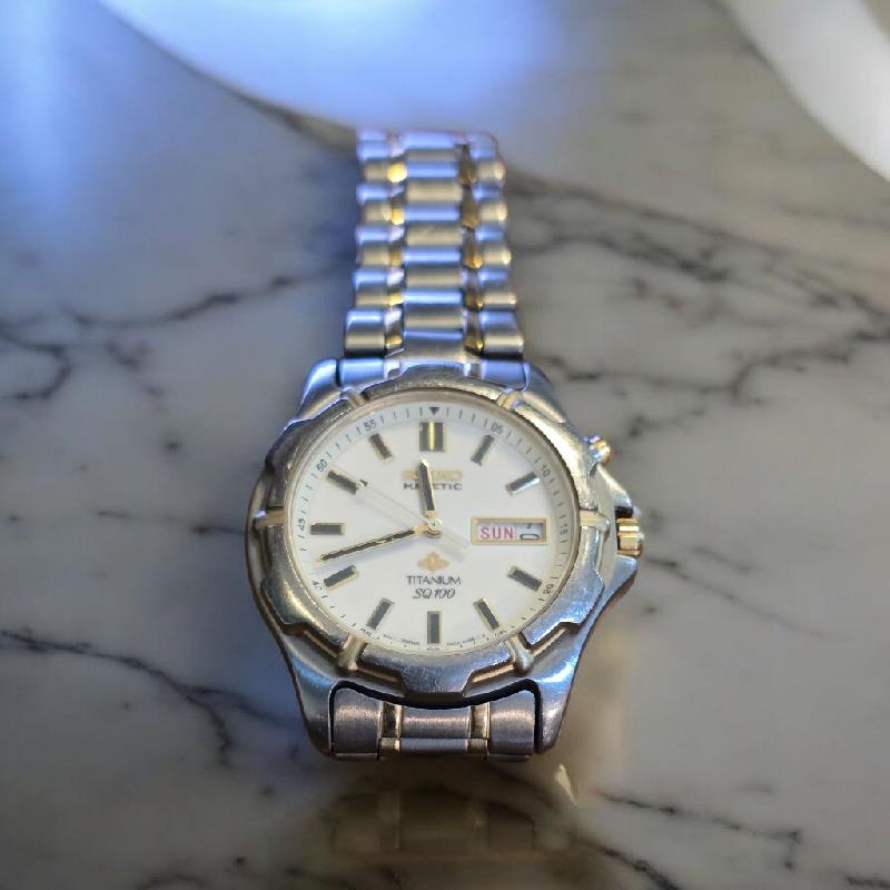 Seiko Kinetic Titanium SQ100 watch with black dial and stainless steel bracelet, showcasing sleek design and precise timekeeping.