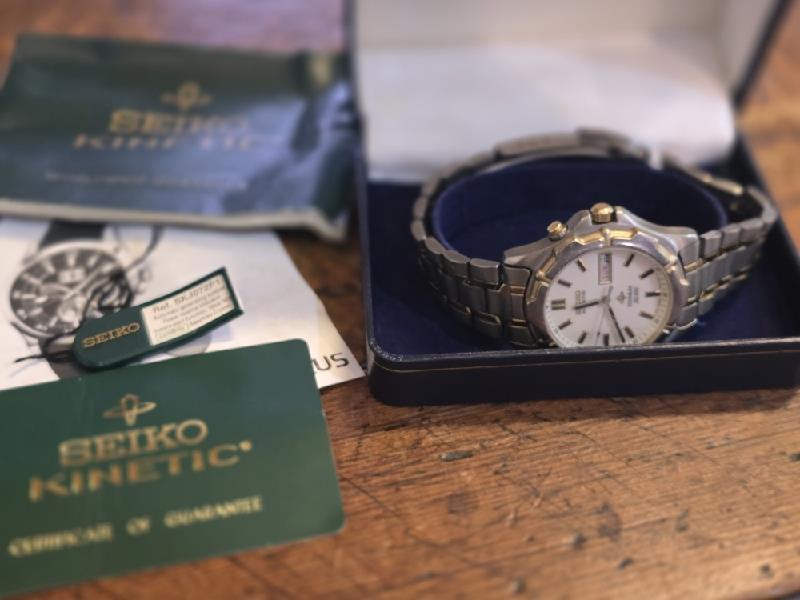 Seiko Kinetic Titanium SQ100 watch with a sleek silver dial and stainless steel band, showcasing precise timekeeping.