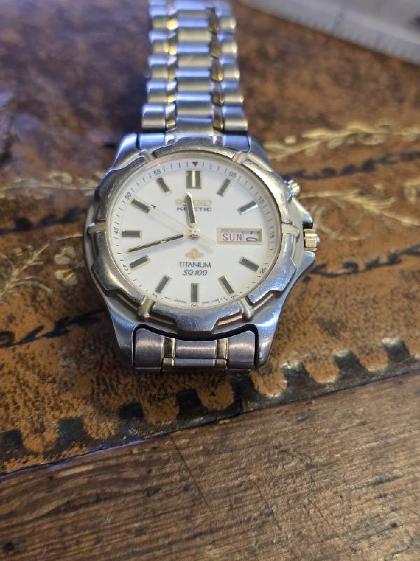 Seiko kinetic titanium SQ100 watch with black dial and stainless steel band, showcasing a sleek, modern design.