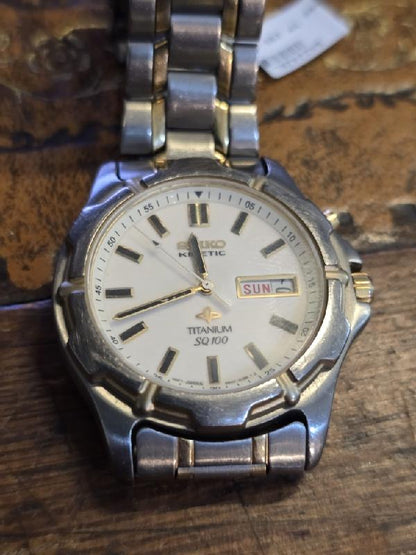 Seiko Kinetic Titanium SQ100 watch with black dial and stainless steel bracelet, showcasing sleek, modern design.