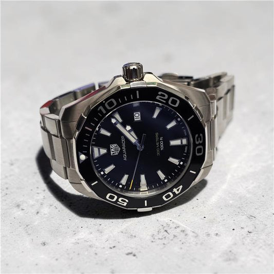 TAG Heuer Aquaracer 300 meters watch with black dial, stainless steel case, and rotating bezel.