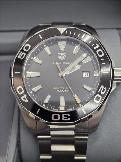 TAG Heuer Aquaracer 300 meters watch with black dial, stainless steel bracelet, and rotating bezel for diving and sports.