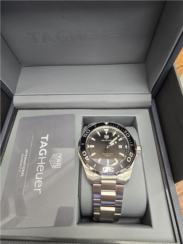 TAG Heuer Aquaracer 300 Meters watch with black dial and stainless steel bracelet, showcasing its sporty diver design.