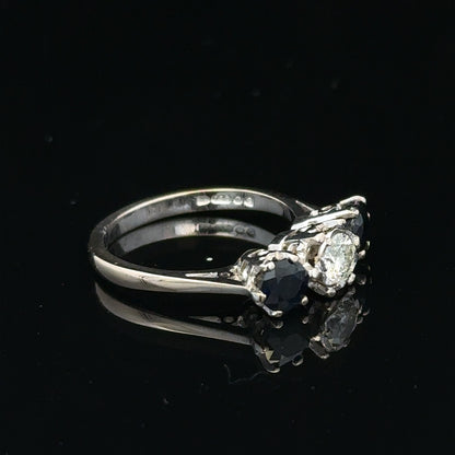 18ct white gold sapphire and diamond ring with a central blue sapphire and sparkling diamonds, displayed on a neutral background.