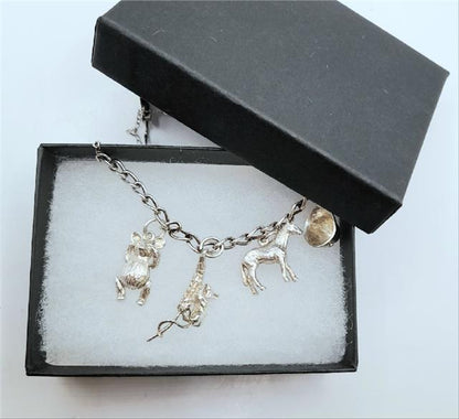 925 silver charm bracelet with intricate designs, unbranded, weighing 27.3g, showcasing detailed charms and polished silver finish.