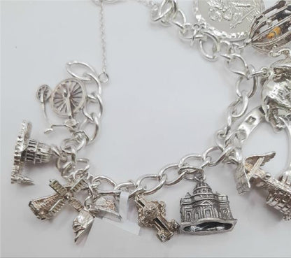 Silver charm bracelet made of 925 silver, 7 inches long, weighing 53.6g, featuring various decorative charms.