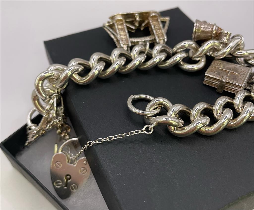 Silver charm bracelet with intricate designs, crafted from 925 silver, featuring multiple decorative charms and a secure clasp.