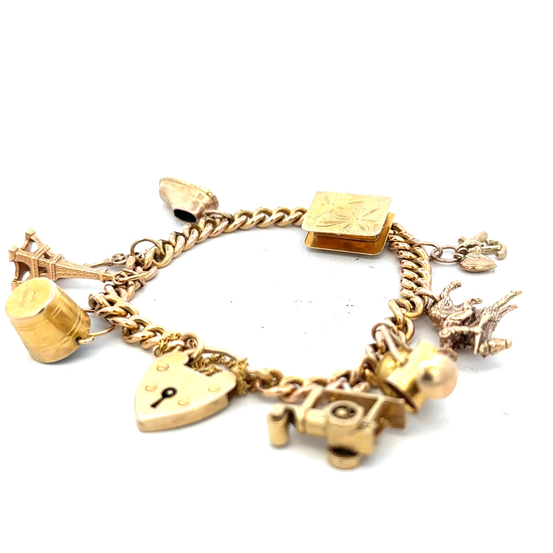 9ct yellow gold charm bracelet weighing 28.1g, unbranded, featuring various decorative charms on a classic gold bracelet.