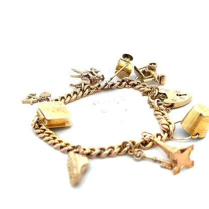 9ct yellow gold charm bracelet with intricate details, weighing 28.1g, featuring delicate charms on a linked gold chain.