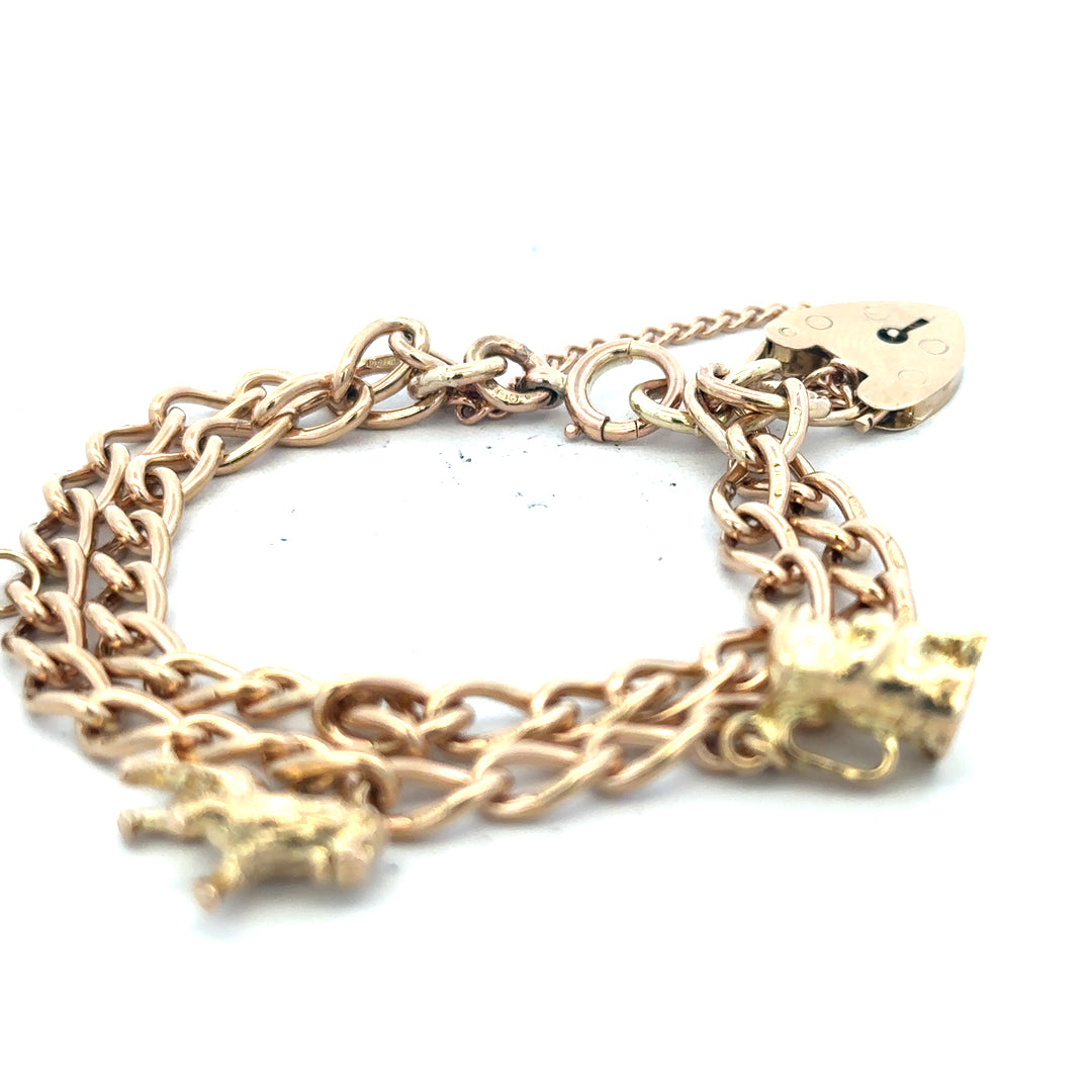 9ct yellow gold charm bracelet with intricate designs, weighing 28.5g, featuring various decorative charms on a classic bracelet style.