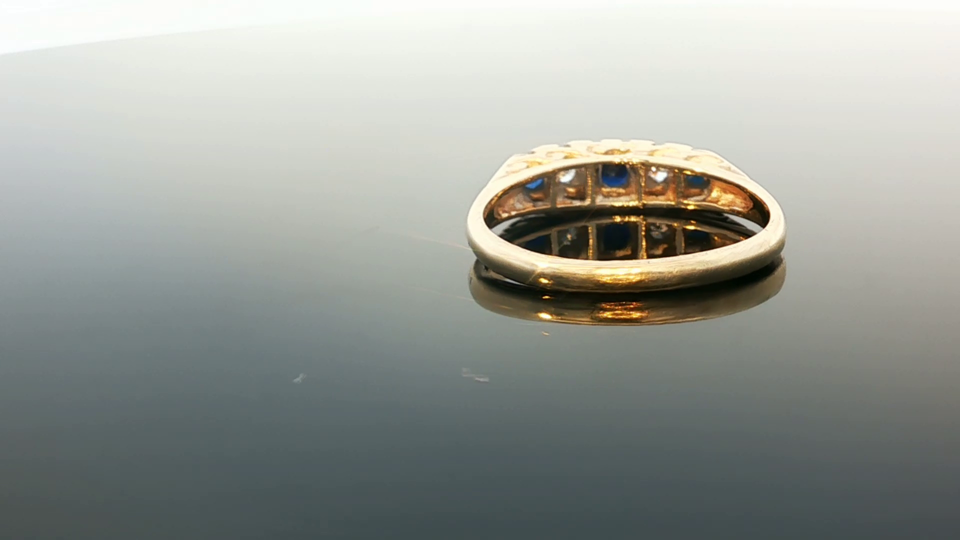 9ct yellow gold ring with diamonds and sapphires, featuring intricate design and gemstone accents.