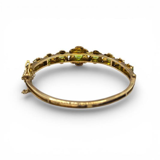 9ct yellow gold peridot bangle bracelet with vibrant green gemstones on a sleek gold band.
