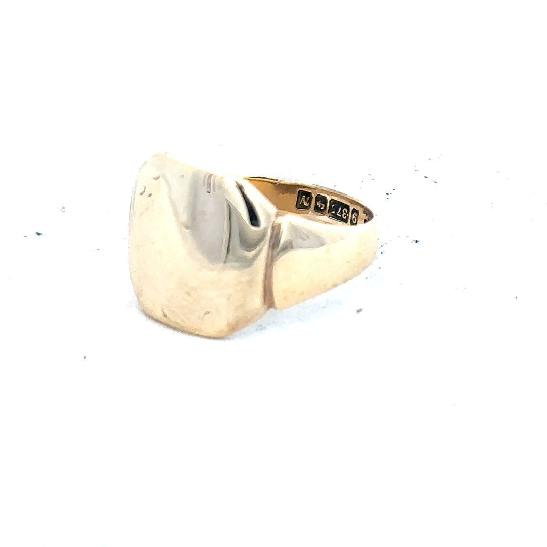 9ct yellow gold signet ring in size J, unbranded with a smooth polished surface, showcased on a neutral background.