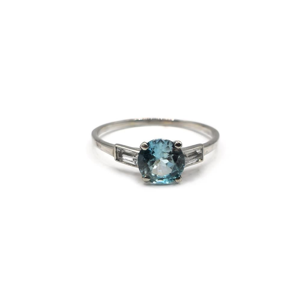 Platinum topaz and cubic zirconia ring featuring a central blue gemstone and sparkling stones on a sleek band.