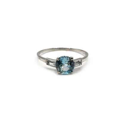 Platinum topaz and cubic zirconia ring featuring a central blue gemstone and sparkling stones on a sleek band.