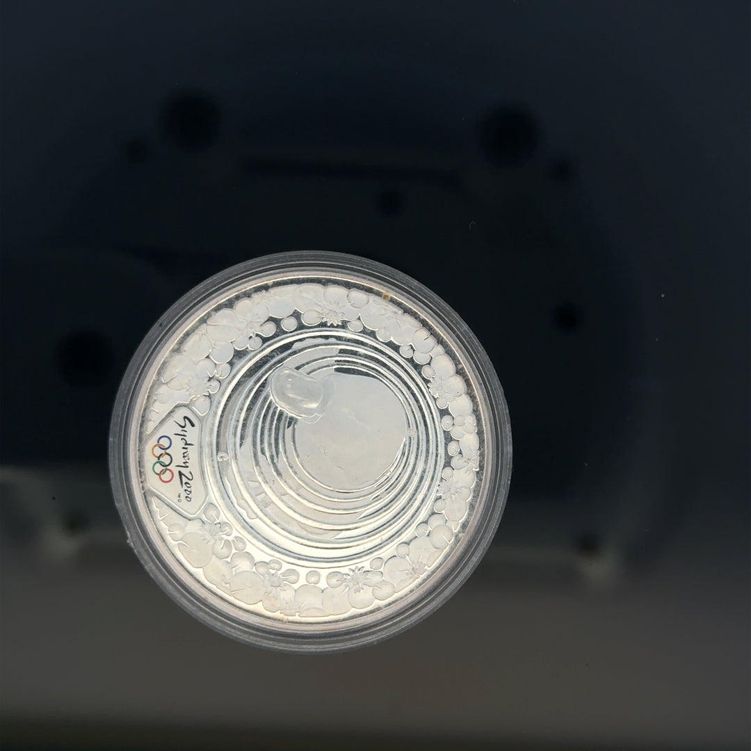 Silver 2000 Olympic coin, 31.4g, unbranded, featuring Olympic imagery and detailed design on a shiny silver surface.