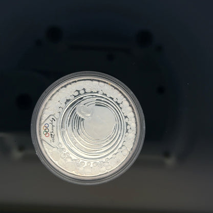 Silver 2000 Olympic coin, 31.4g, unbranded, featuring Olympic imagery and detailed design on a shiny silver surface.