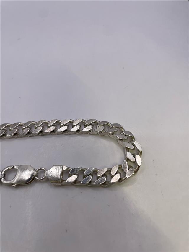 Silver bracelet weighing 33.8g with intricate design, unbranded jewelry piece showcasing polished metal and detailed craftsmanship.