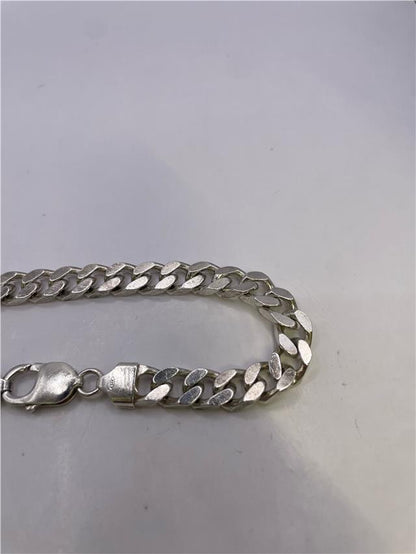 Silver bracelet weighing 33.8g with intricate design, unbranded jewelry piece showcasing polished metal and detailed craftsmanship.