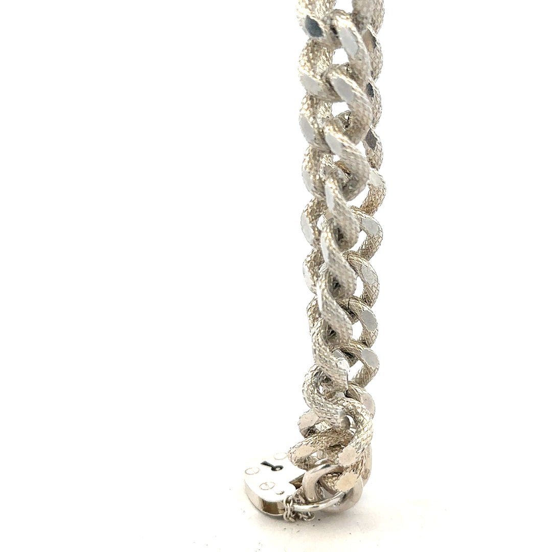 Silver bracelet weighing 64.4g with intricate design, unbranded, showcasing its shiny, detailed metalwork.