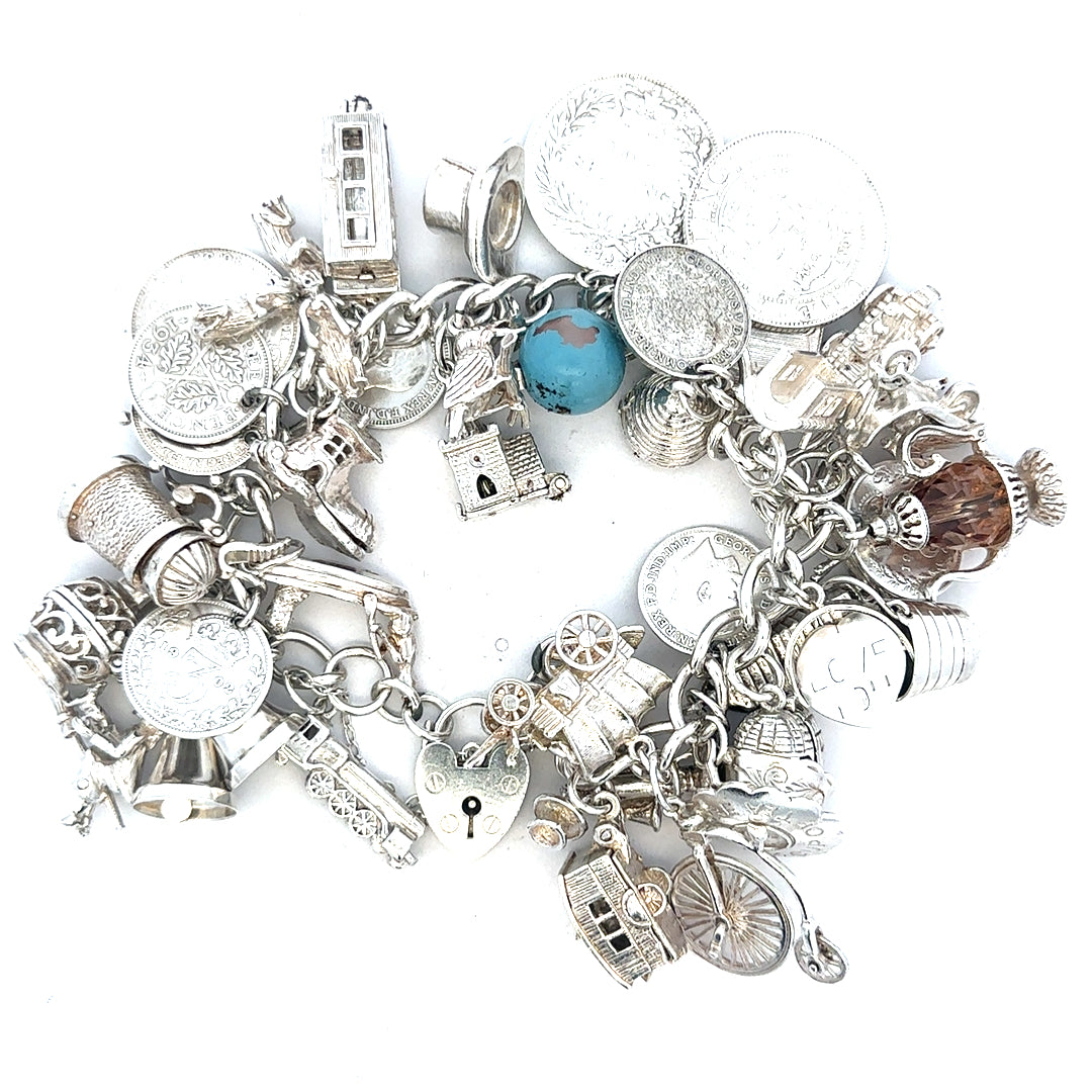 Silver charm bracelet with assorted charms, weighing 128.8g, featuring a stylish and intricate design.